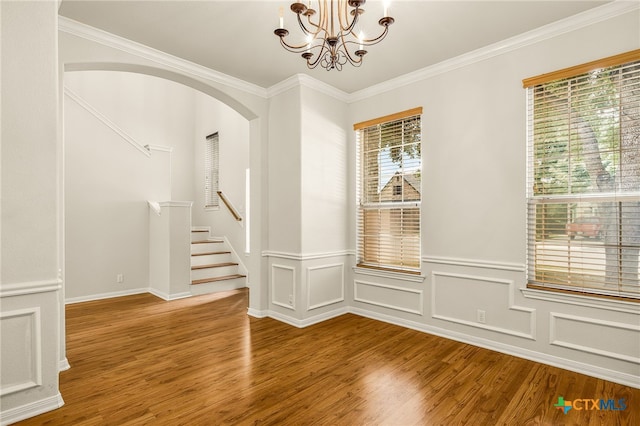 empty room featuring a chandelier, wood-type flooring, and ornamental molding