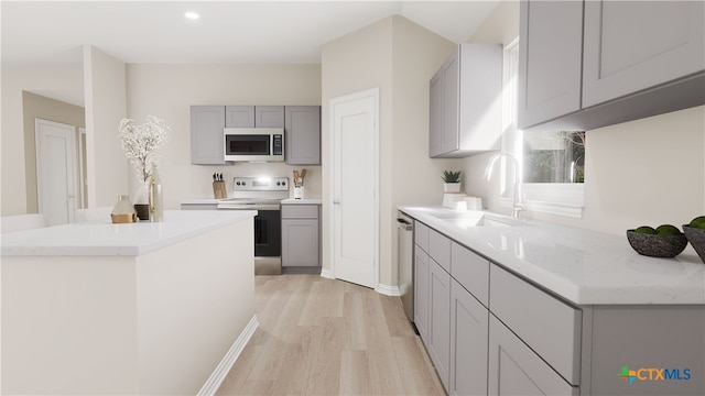 kitchen with sink, appliances with stainless steel finishes, a center island, gray cabinets, and light wood-type flooring