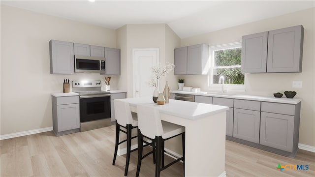 kitchen with gray cabinets, stainless steel appliances, sink, and light wood-type flooring