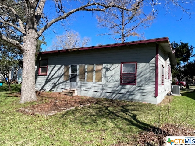 view of front of property with a front yard and central AC