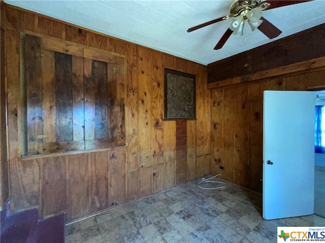 unfurnished room featuring wood walls and ceiling fan