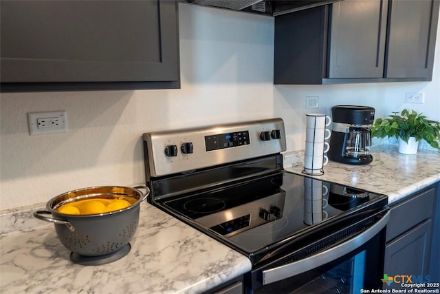 kitchen with stainless steel electric stove and light stone countertops