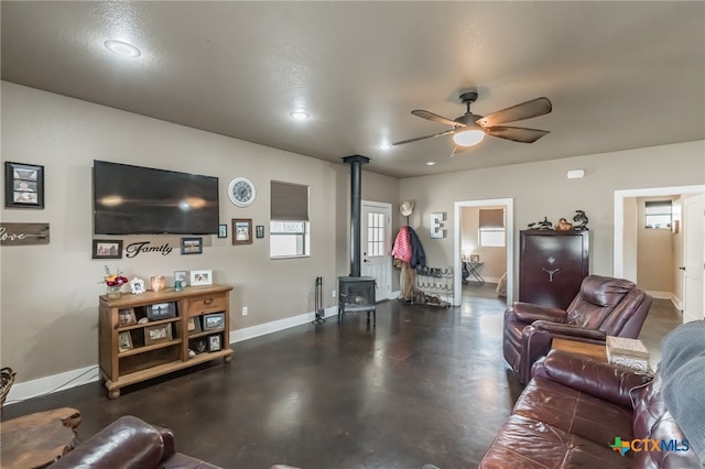 living room with a wood stove, a textured ceiling, and ceiling fan