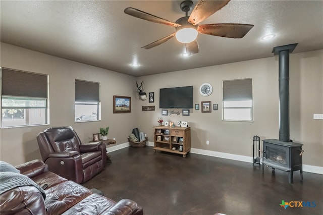 living room with ceiling fan, a textured ceiling, and a wood stove