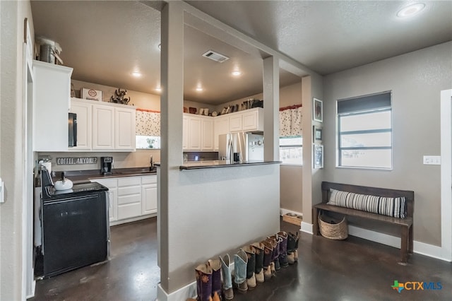 kitchen with black appliances, sink, white cabinetry, and a textured ceiling