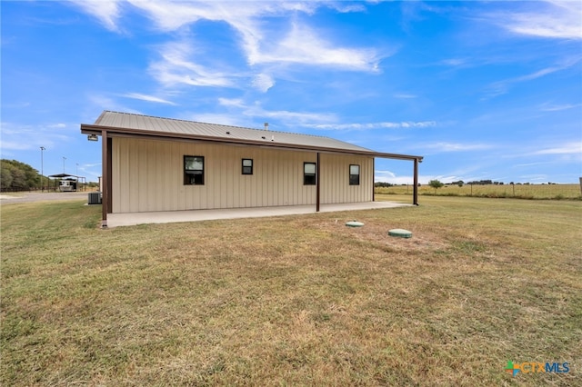 back of house with central air condition unit and a lawn