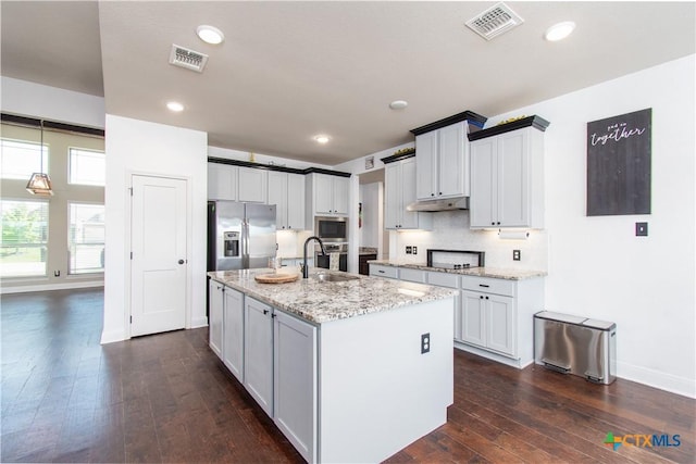 3814 Twilight Dr, Temple, TX 76502 - kitchen featuring stainless steel appliances, dark wood-type flooring, light stone countertops, under cabinet range hood, and an island with sink