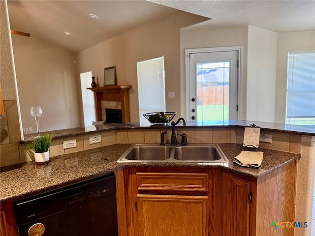 3508 Lucas St, Copperas Cove, TX 76522 - kitchen featuring dishwasher, a sink, brown cabinetry, a tile fireplace, and dark stone countertops
