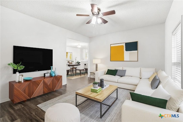 living room featuring a textured ceiling, ceiling fan, and dark wood-type flooring