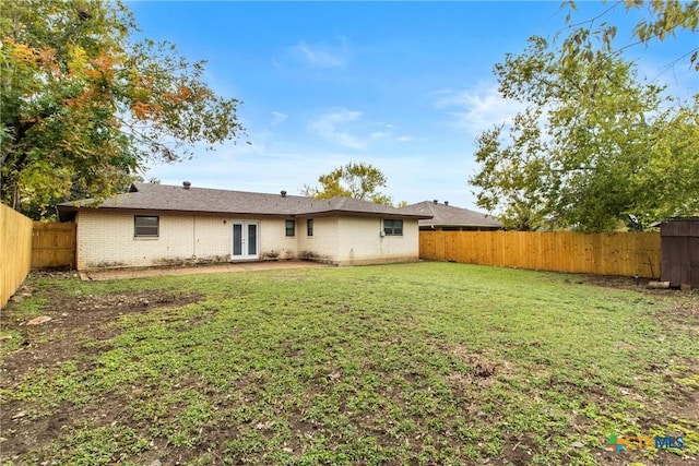 rear view of property with french doors and a yard