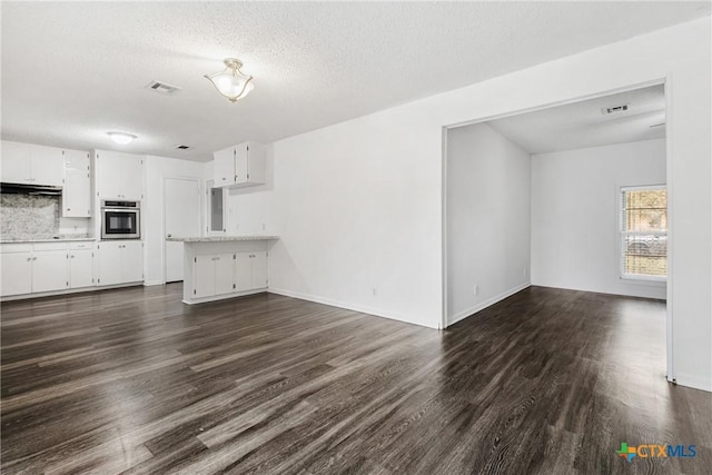 unfurnished living room with a textured ceiling and dark wood-type flooring