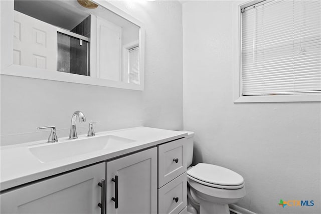 bathroom featuring vanity, an enclosed shower, and toilet