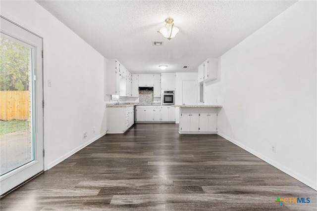 kitchen featuring dark wood-type flooring, white cabinets, oven, sink, and a textured ceiling