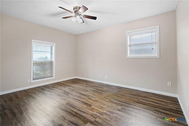 spare room with a textured ceiling, ceiling fan, and dark hardwood / wood-style floors