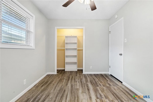 unfurnished bedroom featuring wood-type flooring, a walk in closet, a closet, and ceiling fan