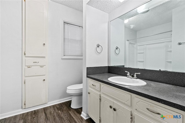 bathroom featuring vanity, toilet, a textured ceiling, walk in shower, and wood-type flooring