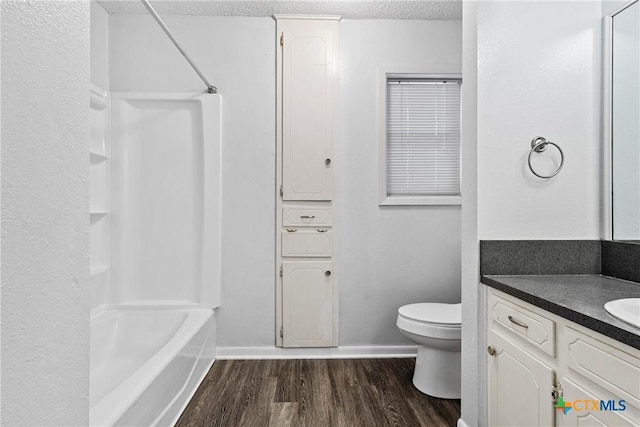 full bathroom featuring wood-type flooring, a textured ceiling, toilet, shower / washtub combination, and vanity