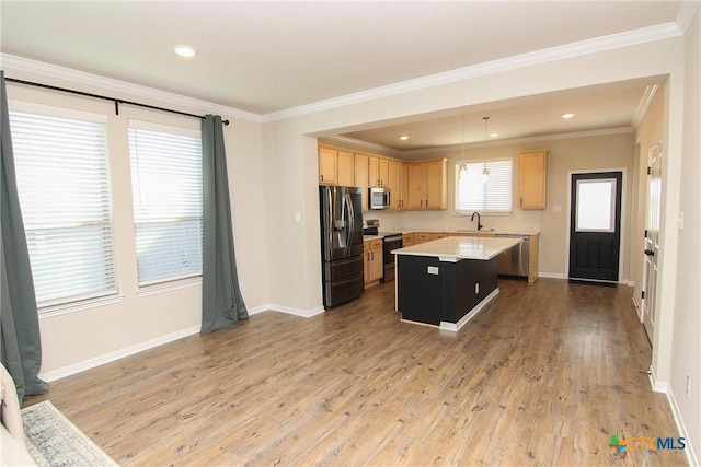 kitchen with appliances with stainless steel finishes, ornamental molding, light hardwood / wood-style flooring, a center island, and hanging light fixtures