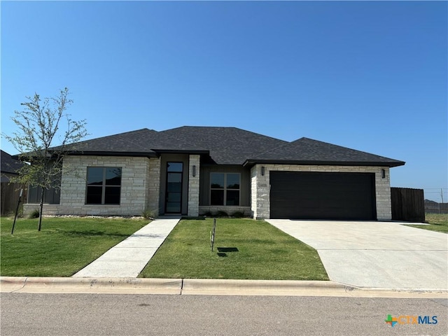 view of front of house with a shingled roof, concrete driveway, fence, a garage, and a front lawn