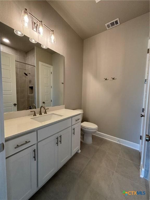 full bath with tile patterned flooring, vanity, visible vents, baseboards, and a tile shower