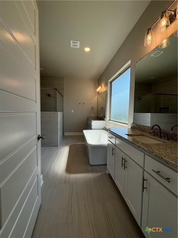 bathroom featuring visible vents, a soaking tub, wood finished floors, vanity, and a shower stall