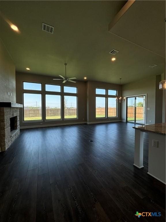 unfurnished living room with a fireplace, dark wood finished floors, visible vents, and a ceiling fan