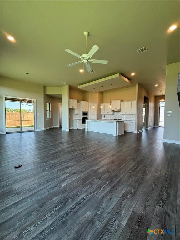 unfurnished living room featuring baseboards, visible vents, a ceiling fan, dark wood-style floors, and recessed lighting