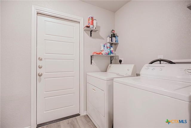 laundry area with light hardwood / wood-style floors and washing machine and dryer