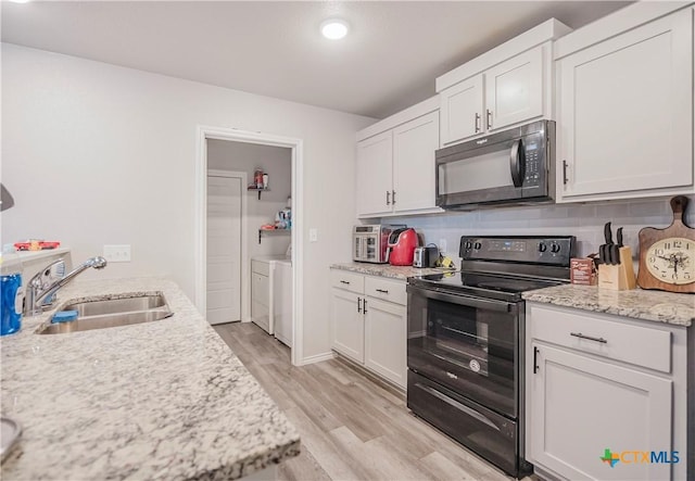 kitchen featuring independent washer and dryer, black appliances, decorative backsplash, white cabinets, and sink