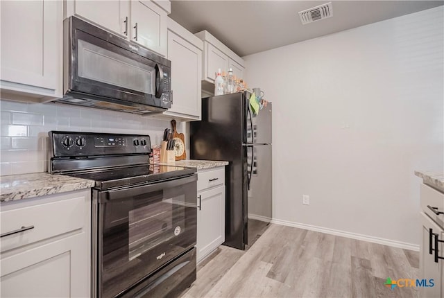 kitchen featuring black appliances, light hardwood / wood-style floors, white cabinets, and light stone counters