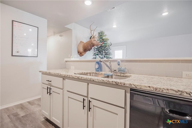 kitchen with light stone counters, dishwasher, light hardwood / wood-style flooring, white cabinets, and sink