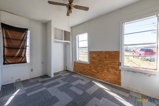 unfurnished bedroom with dark colored carpet, a closet, and ceiling fan