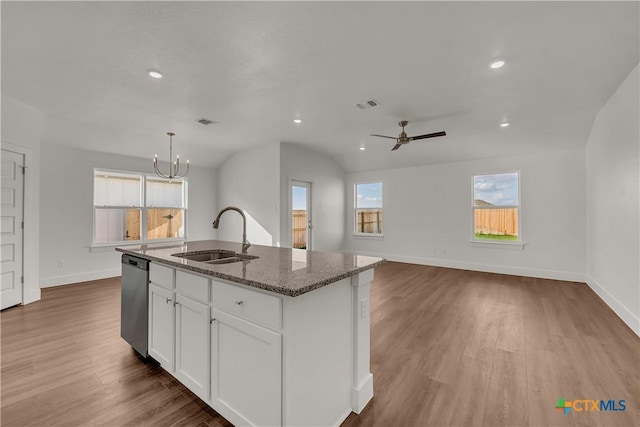 kitchen with stone counters, sink, white cabinets, hanging light fixtures, and a kitchen island with sink