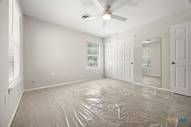 unfurnished bedroom featuring light carpet, multiple windows, and ceiling fan