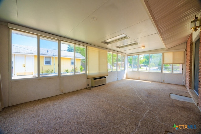 unfurnished sunroom featuring plenty of natural light, an AC wall unit, and vaulted ceiling