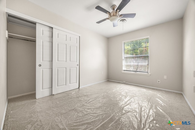 unfurnished bedroom featuring light carpet, ceiling fan, and a closet