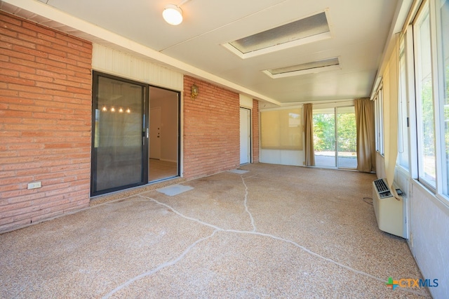 unfurnished sunroom with a wall mounted air conditioner