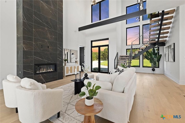 living room featuring a healthy amount of sunlight, a towering ceiling, a fireplace, and french doors