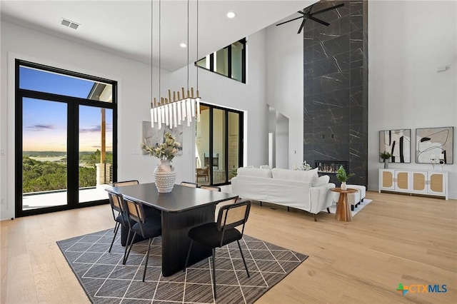 dining area featuring ceiling fan, wood-type flooring, a towering ceiling, and french doors