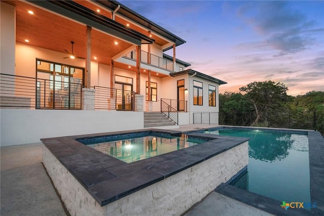 pool at dusk with an in ground hot tub