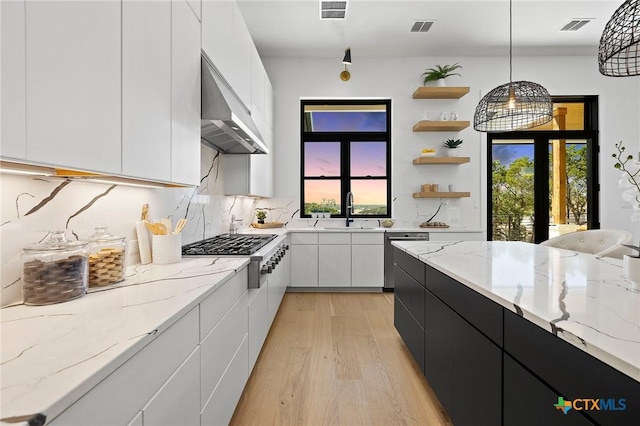 kitchen with white cabinetry, sink, wall chimney exhaust hood, stainless steel appliances, and pendant lighting