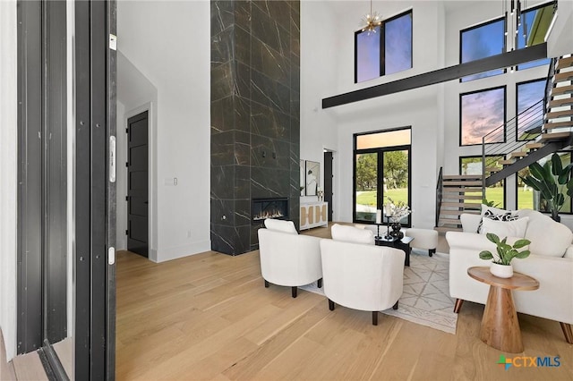 living room with wood-type flooring, a towering ceiling, a high end fireplace, and french doors