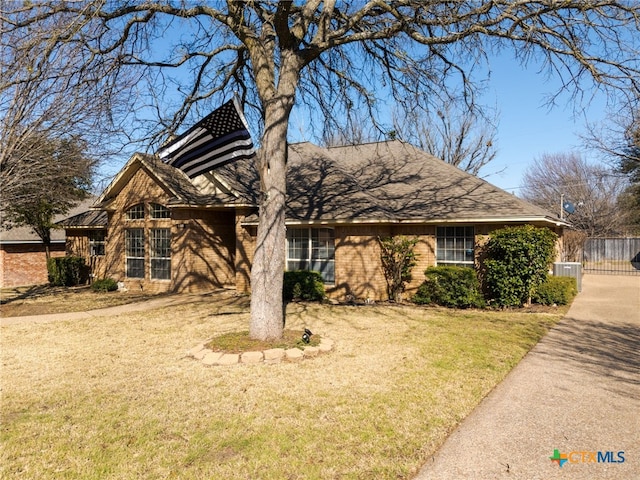 view of front of property featuring a front yard, fence, central AC, and brick siding