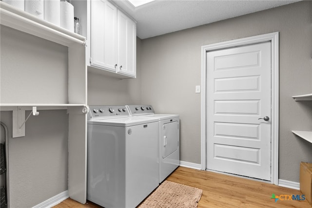 laundry area with cabinet space, baseboards, washer and clothes dryer, and light wood-style floors