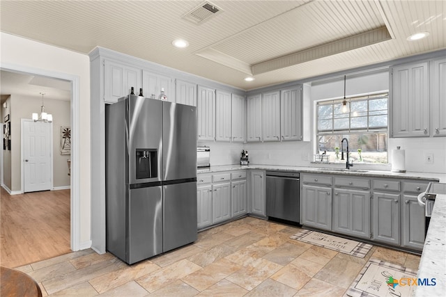 kitchen featuring a tray ceiling, gray cabinets, visible vents, appliances with stainless steel finishes, and a sink