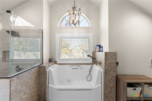 bathroom featuring a jetted tub, an inviting chandelier, vaulted ceiling, and tiled shower