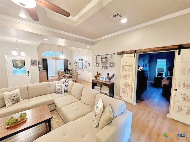 living room featuring a barn door, light wood-type flooring, and crown molding