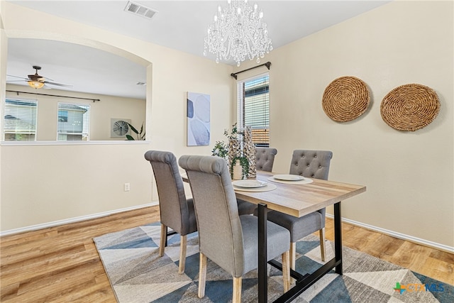 dining space featuring wood-type flooring and ceiling fan with notable chandelier