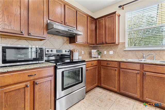 kitchen with sink, light stone counters, decorative backsplash, light tile patterned floors, and appliances with stainless steel finishes