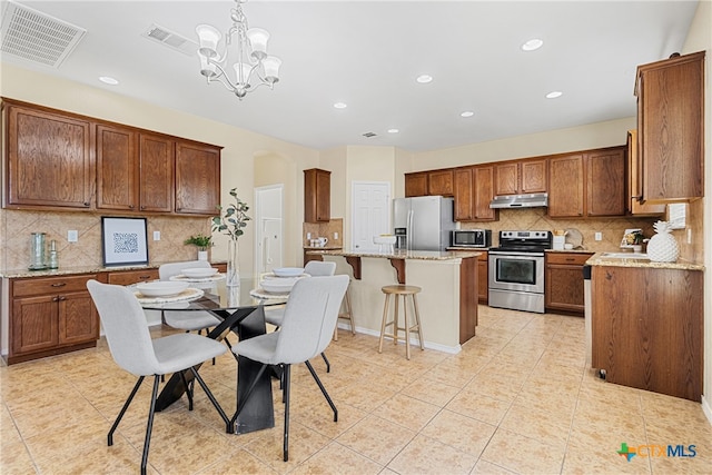 kitchen with decorative backsplash, appliances with stainless steel finishes, a center island, and decorative light fixtures